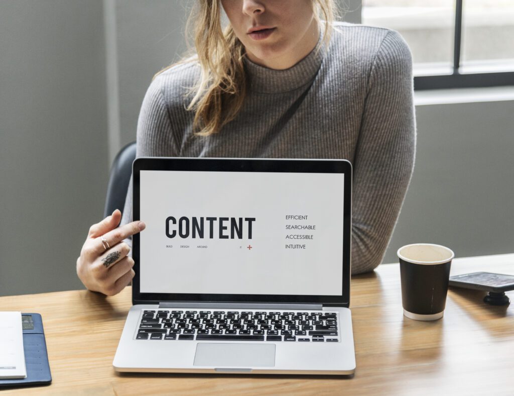 blond woman pointing laptop screen