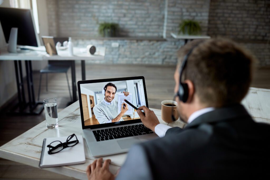 male entrepreneur using laptop while having online meeting talking his colleague about business reports focus is laptop screen